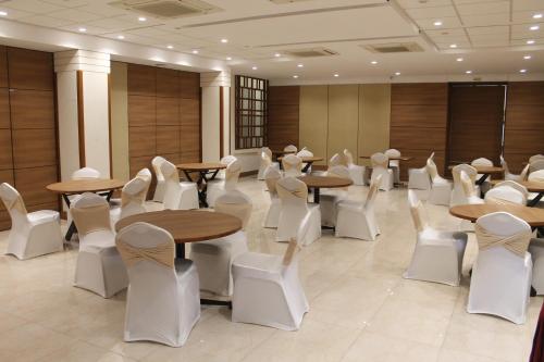 una habitación llena de mesas y sillas blancas en Chryso Hotels Pvt Ltd, en Ankleshwar