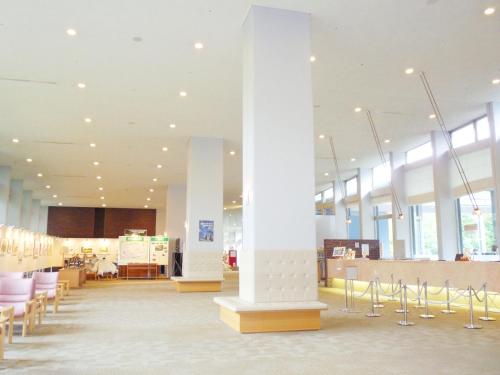 a lobby with white columns and tables and chairs at Shin Furano Prince Hotel in Furano