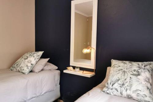 a bedroom with a mirror next to a bed and a mirror at Ducks Nest in Malelane