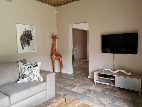 a living room with a couch and a tv and a giraffe at Ducks Nest in Malelane
