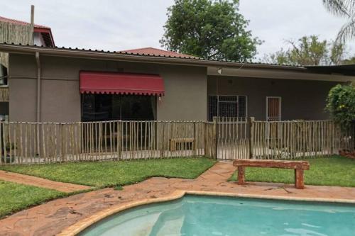 a house with a swimming pool and a wooden fence at Ducks Nest in Malelane