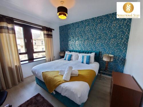 - une chambre dotée d'un lit avec un mur bleu dans l'établissement 4 Bedroom Apartment By Sensational Stay Short Lets & Serviced Accommodation, Aberdeen , Roslin Street With Free Wi-fi & Netflix, à Aberdeen