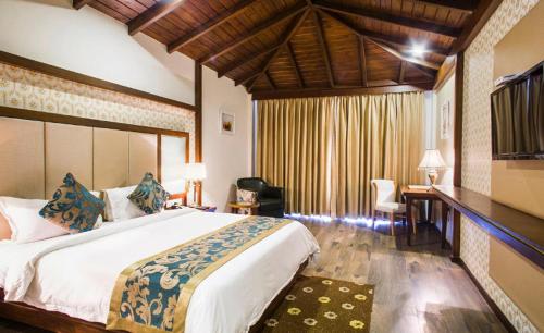 um quarto com uma cama grande, uma secretária e uma cadeira. em The Fern Hillside Resort Bhimtal em Bhīm Tāl