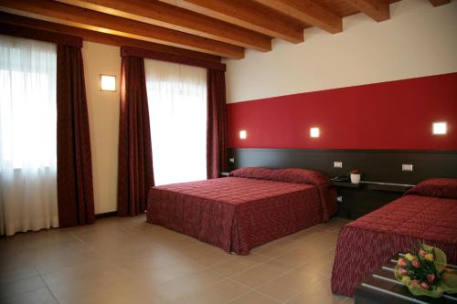 pokój hotelowy z 2 łóżkami i czerwoną ścianą w obiekcie Corte Della Rocca Bassa w mieście Nogarole Rocca