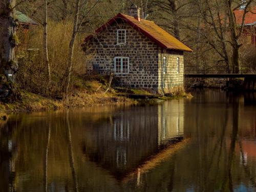 an old house sitting on the side of a body of water at Kvarnen i Borgvik in Borgvik