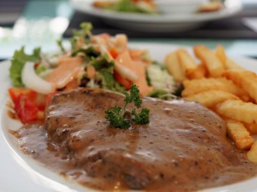 a plate of food with meat and french fries at Pattaya Blue Sky in Pattaya Central