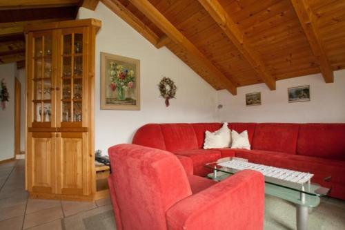 a living room with a red couch and a glass table at Kleinreiterhof in Bad Reichenhall