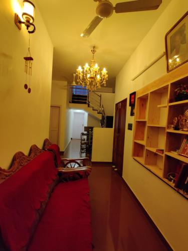 a living room with a red couch and a chandelier at Calvin's Inn in Cochin