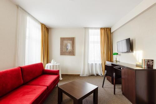 a living room with a red couch and a tv at Old Town Hotel Bohema, Klaipėda in Klaipėda