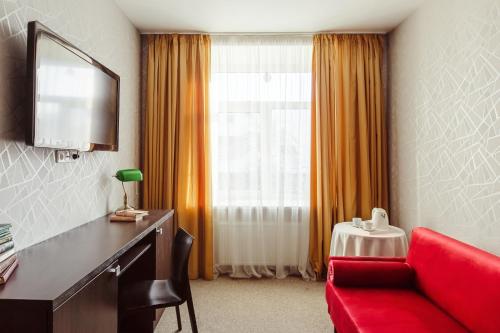 a hotel room with a red couch and a window at Old Town Hotel Bohema, Klaipėda in Klaipėda