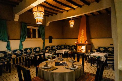 a dining room with tables and chairs and a fireplace at Ksar Bicha in Merzouga