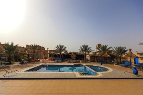 a large swimming pool in a resort with palm trees at Ksar Bicha in Merzouga