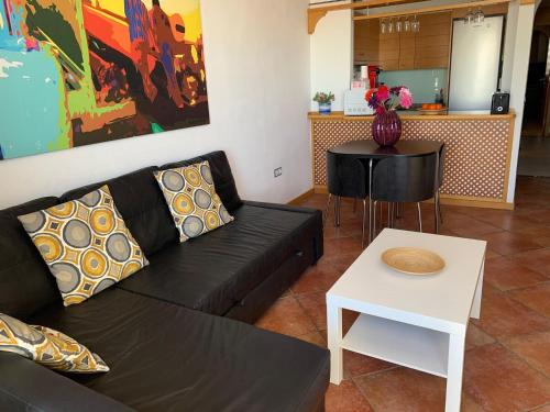 een woonkamer met een zwarte bank en een tafel bij Adeje Paradise en Playa Paraiso in Adeje