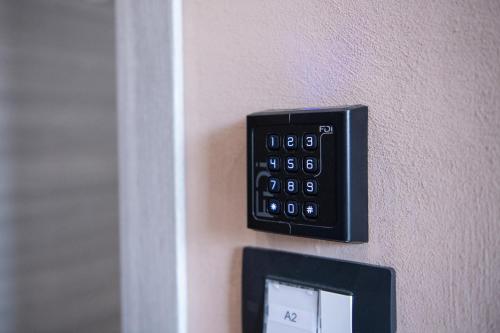 a black remote control on a wall with a clock at Le PALME in Parma