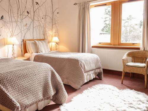 a bedroom with two beds and a window and a chair at Torview House in Peebles