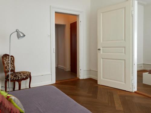 a bedroom with a bed and a door and a chair at Apartments Spalenring 10 in Basel