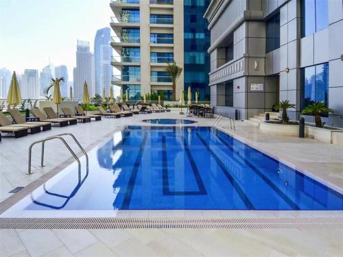 a large swimming pool with chairs and a building at Luxury Rooms In The Tallest Tower In Marina-BeachFront Atlantis & Skydive View in Dubai