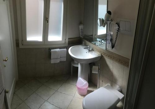 a bathroom with a sink and a toilet and a mirror at B&B a le Boteghe in Venice