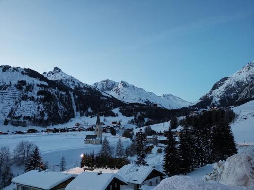 a village in the snow with mountains in the background at SCOL Sporthotel Großglockner in Kals am Großglockner