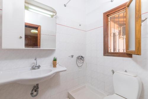 a bathroom with a sink and a toilet and a window at Nikos Pool Apartments - Ground Floor in Sidari