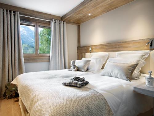 Un dormitorio con una gran cama blanca con un osito de peluche. en Les Chalets Laska en Les Contamines-Montjoie