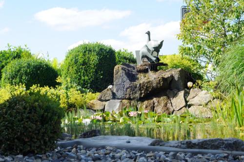 a statue of a cat sitting on a rock in a garden at Hotel Schwarzes Ross in Schwarzach am Main
