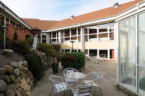 VissenbjergにあるHotel Vissenbjerg Storkroの建物の前にパティオ(テーブル、椅子付)