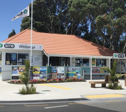 a white building with a bench in front of it at Whitianga Motel in Whitianga