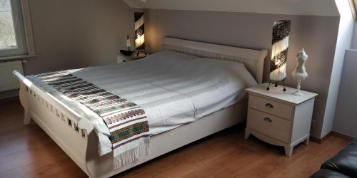 - une chambre avec un lit blanc et une table de nuit dans l'établissement Le bordon, à Durnal