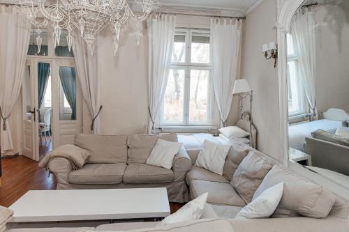 a living room with a couch and a chandelier at Suites La Bella in Sopot