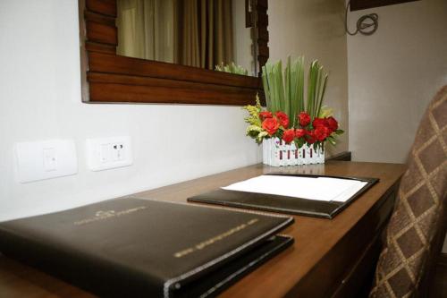 a laptop sitting on a desk with a vase of flowers at Golden Prince Hotel & Suites in Cebu City