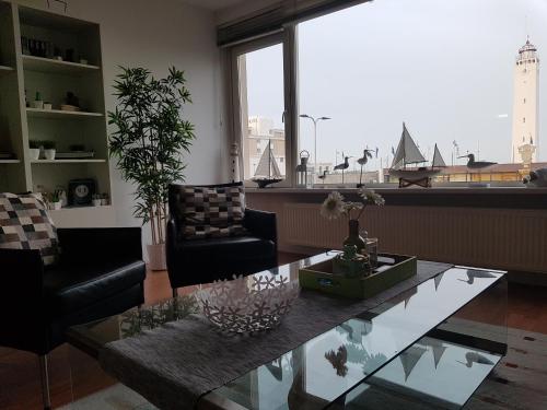 a living room with a coffee table and a large window at Appartement "Zicht op de Vuurtoren" in Noordwijk aan Zee