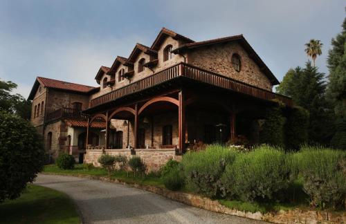 a large brick house with a porch on a road at Jardin de Carrejo in Cabezón de la Sal
