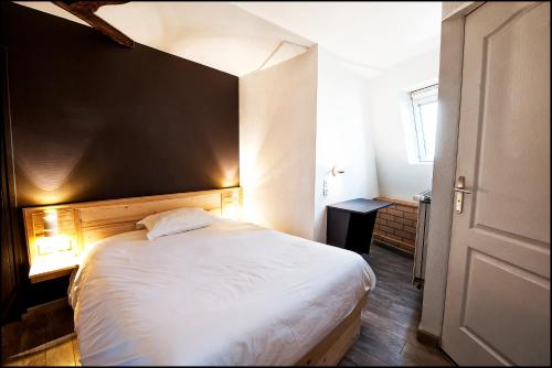 a bedroom with a large white bed with a black wall at Hôtel du Nord in Sainte-Geneviève