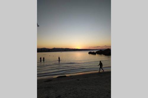 people walking on the beach at sunset at Natasha's Luxury apartment by the sea in Galatás