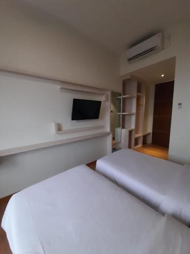 a bedroom with two beds and a flat screen tv at Blitz Hotel Batam Centre in Batam Center