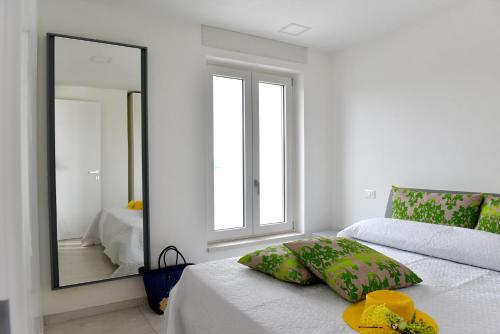 ein weißes Schlafzimmer mit einem Spiegel und einem Bett in der Unterkunft Geranio Apartment - Villaggio di Mary in Locorotondo