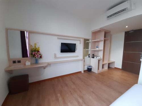 a room with a bed and a television on a wall at Blitz Hotel Batam Centre in Batam Center