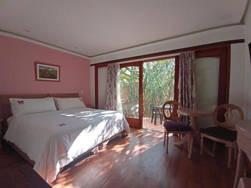 a bedroom with a bed and a table and a window at La Casa Del Arbol Hotel Boutique Villa de Leyva in Villa de Leyva