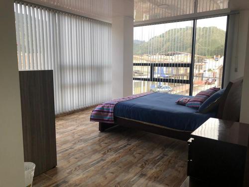 ein Schlafzimmer mit einem Bett und einem großen Fenster in der Unterkunft Casa Bertha Hotel y Servicios SAS in Nobsa
