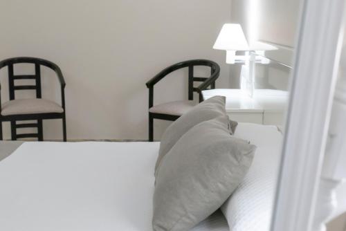a bed with two black chairs and a white pillow at Hotel Ramomar in Tomelloso