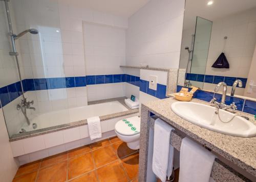 a bathroom with a tub and a toilet and a sink at Hotel Calina in Cadaqués