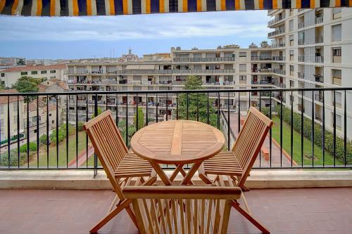 une table en bois et deux chaises sur un balcon dans l'établissement IMMOGROOM - Very Pleasant and Bright - Cozy - Shops, à Cannes