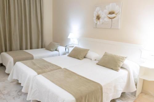 two beds in a hotel room with a flower on the wall at Hotel Ramomar in Tomelloso