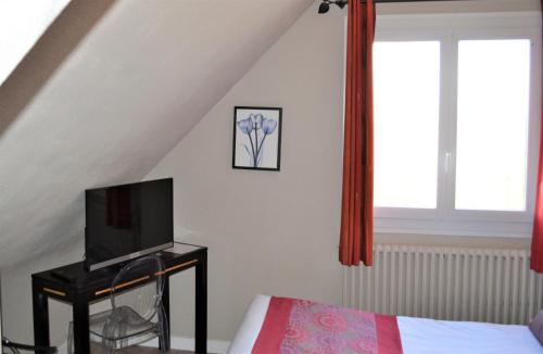 a bedroom with a bed and a tv and a window at The Originals Boutique, Hôtel Les Quatre Salines, Le Mont Saint-Michel Sud in Roz-sur-Couesnon
