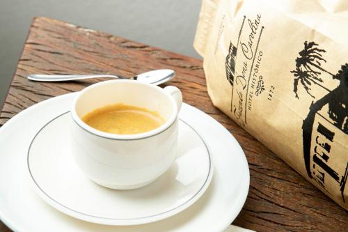 a cup of coffee on a plate next to a bag at Hotel Fazenda Dona Carolina in Itatiba