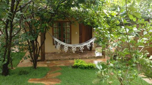 a hammock in front of a house with trees at Chalé Juliet in Pirenópolis