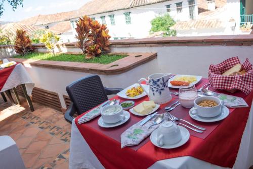 a table with a red table cloth with food on it at La Casa Del Arbol Hotel Boutique Villa de Leyva in Villa de Leyva