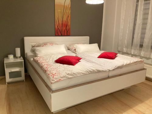 a white bed with two red pillows on it at Ferienwohnung Wittker in Bruttig-Fankel