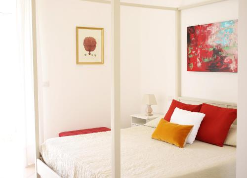 - une chambre blanche avec un lit doté d'oreillers rouges et oranges dans l'établissement Casa Tarantino Charming apartments, à Capri
